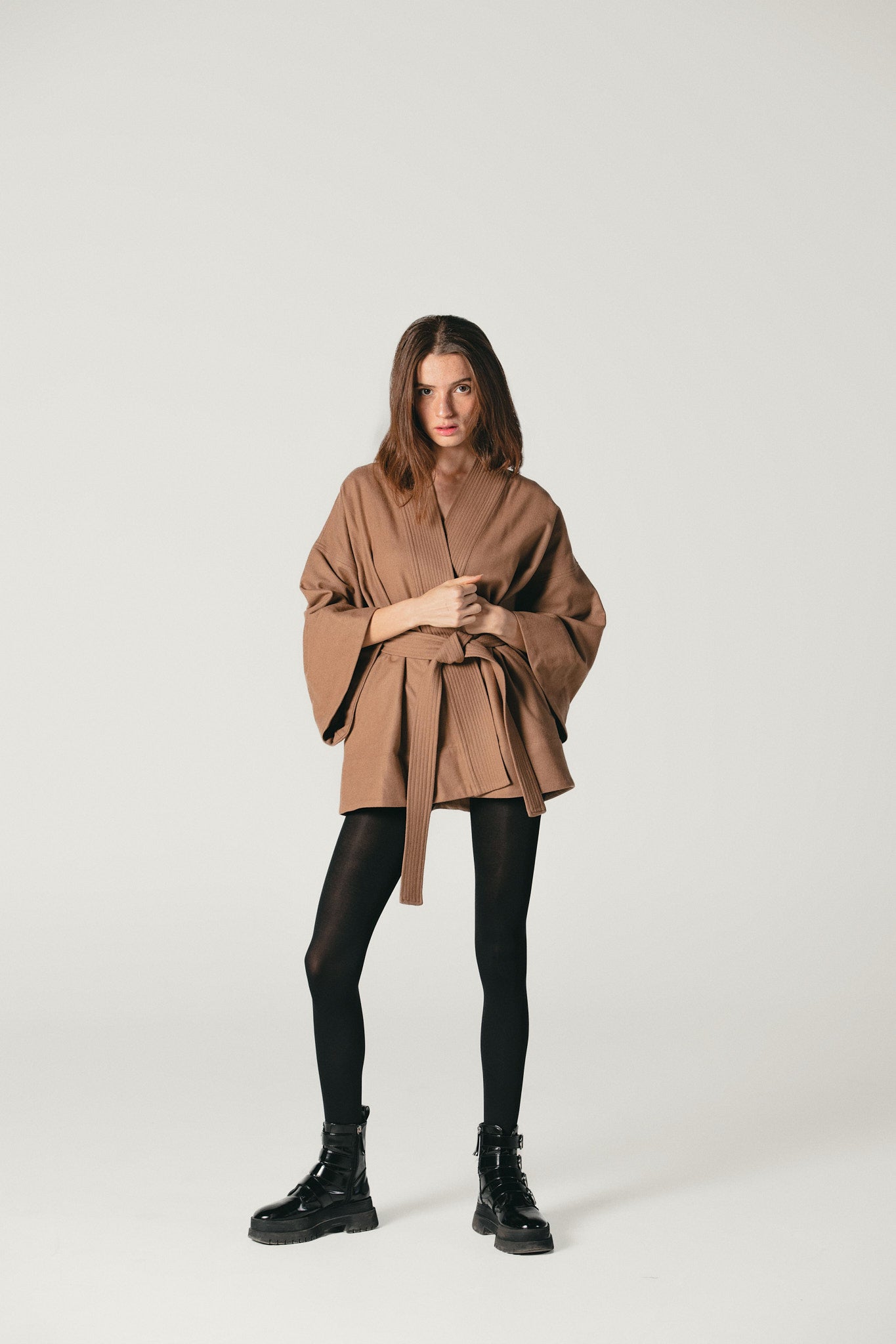 A wide shot of a model wearing a camel Pure Wool kimono jacket made by Atelier Mizuni