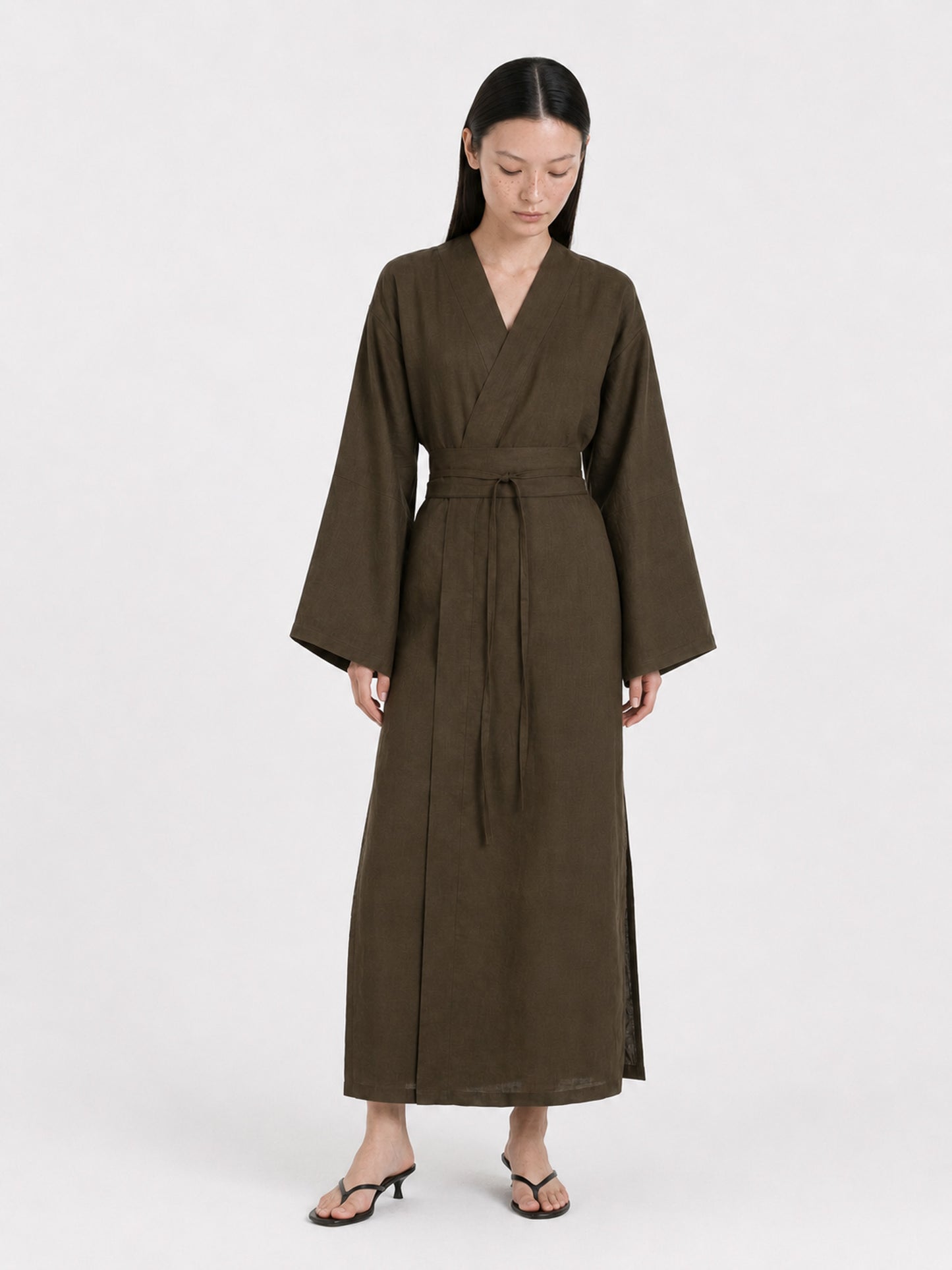 A  model wearing a Dark Olive Linen kimono dress made by atelier mizuni looking down