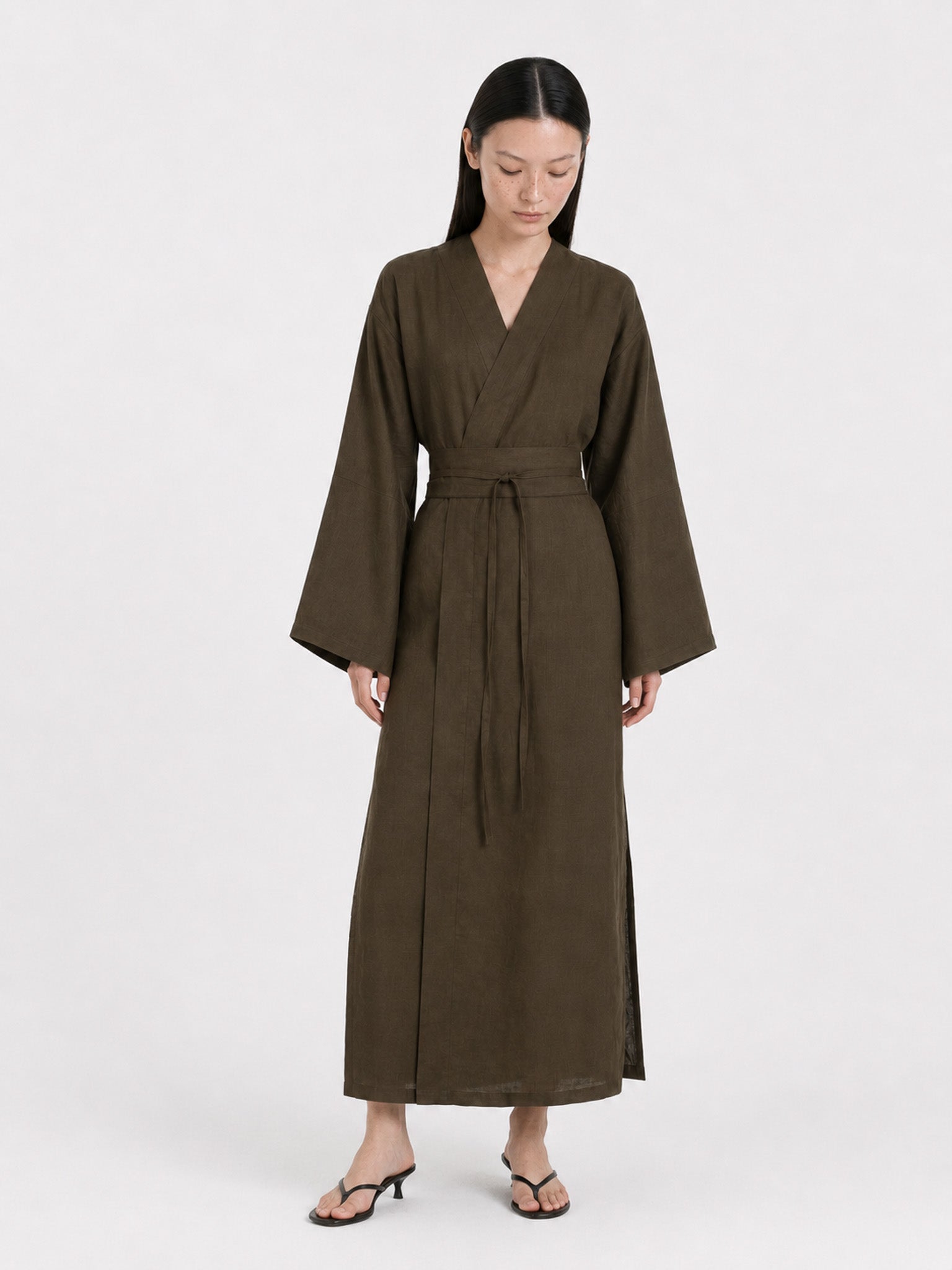 A  model wearing a Dark Olive Linen kimono dress made by atelier mizuni looking down