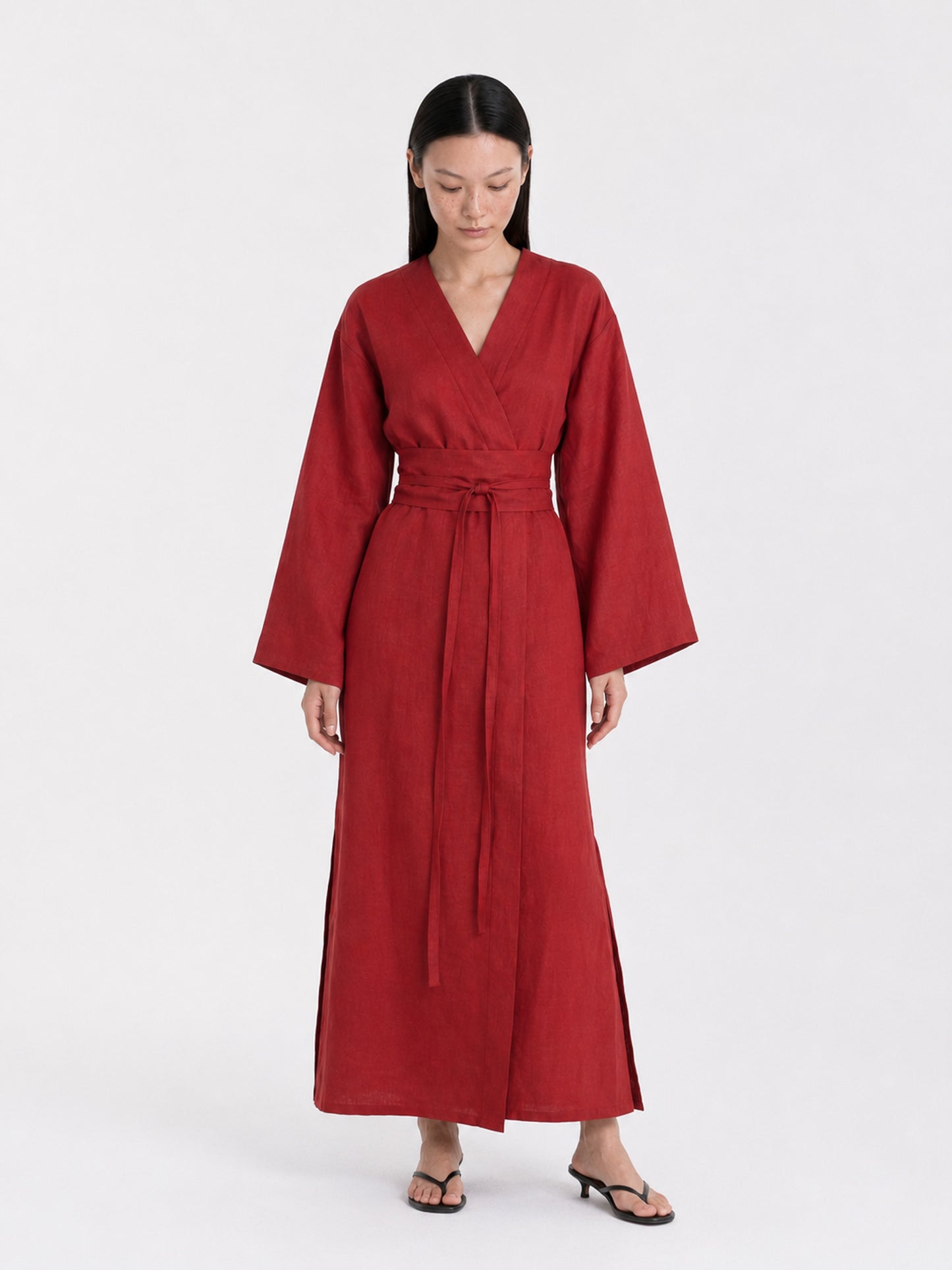 A  model wearing a Red Wine linen kimono dress made by atelier mizuni looking down