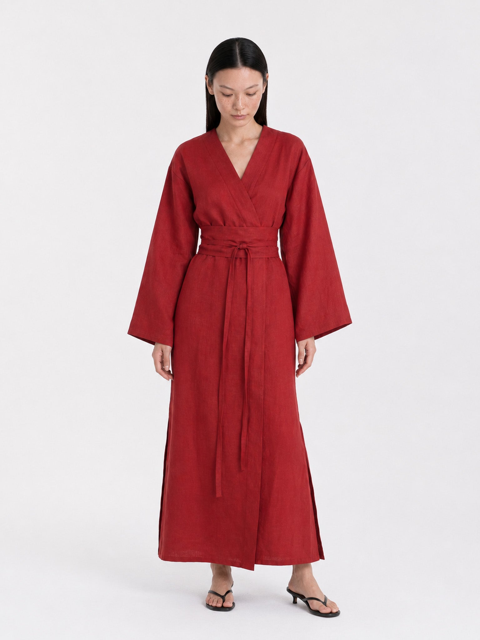 A  model wearing a Red Wine linen kimono dress made by atelier mizuni looking down