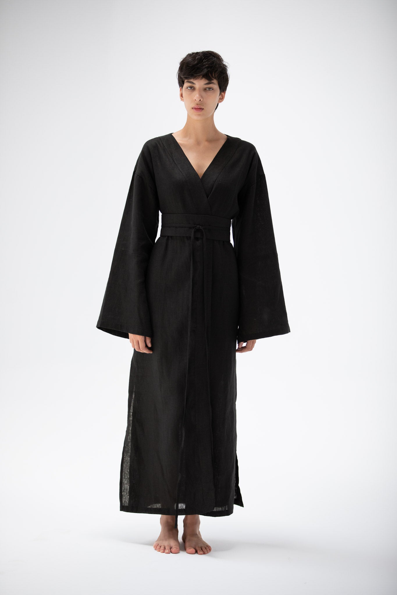 Woman wearing a black kimono dress with wild sleeves made of pure linen.