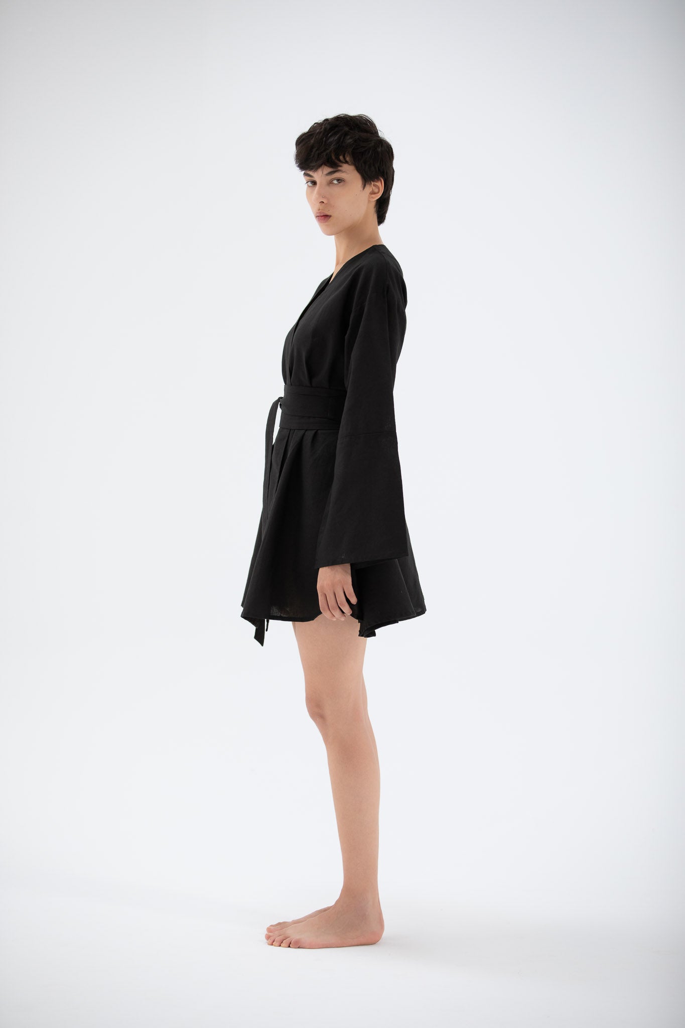 a model wearing a lienn black kimono dress on a white background made by atelier mizuni.