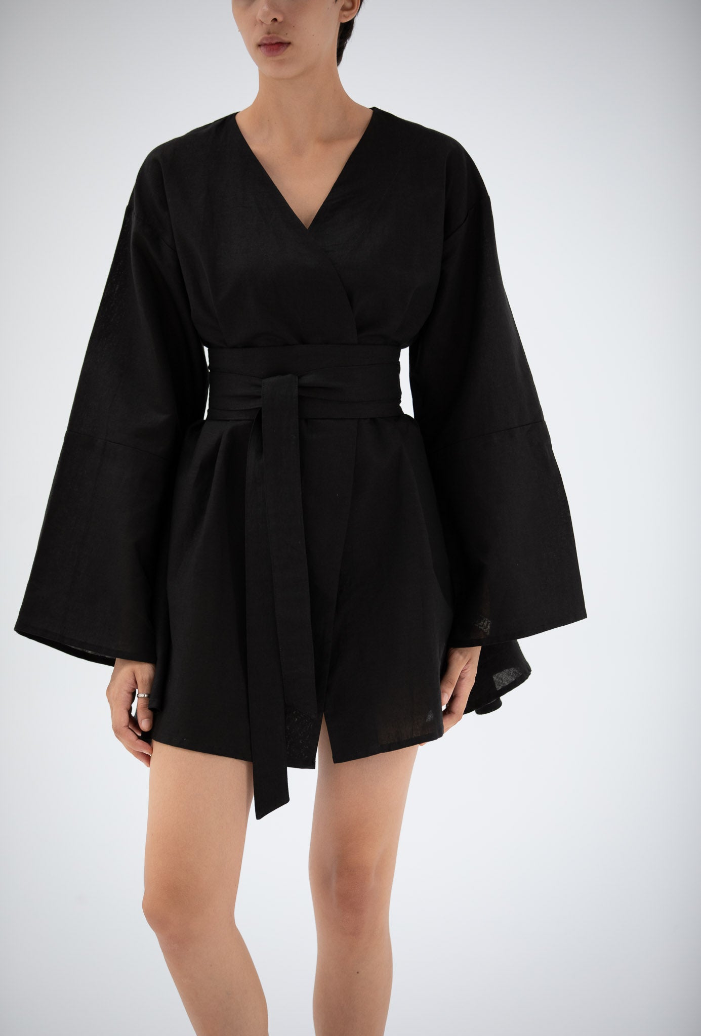 Black kimono-style dress made of linen worn by a model on a white background.