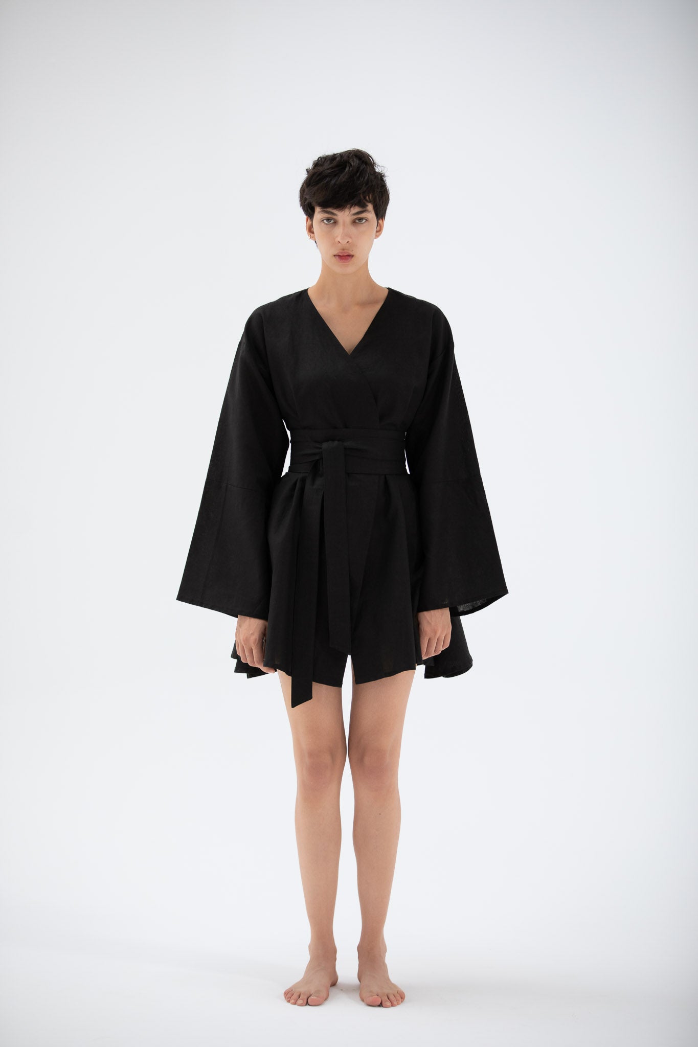 Woman wearing a black kimono-style short dress made of premium linen by atelier mizuni.