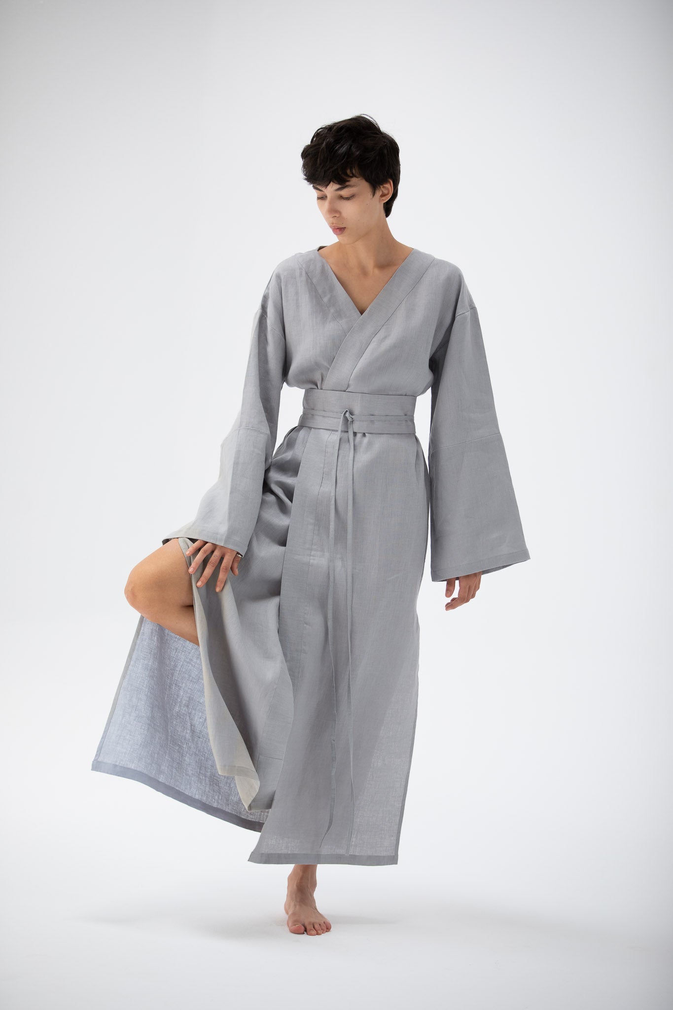 Woman wearing a gray blue kimono-style garment made of pure linen on a white background