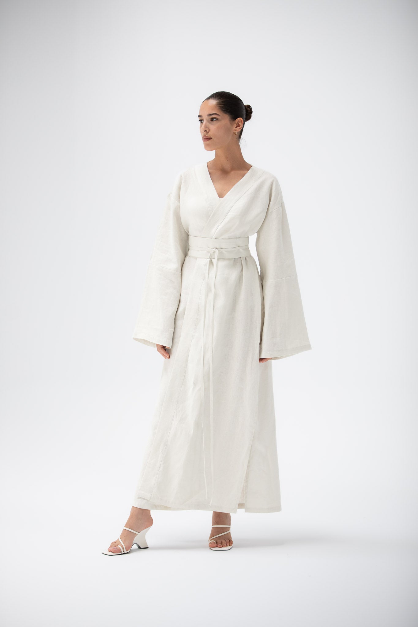Woman wearing an ivory kimono dress with long sleeves on a white background