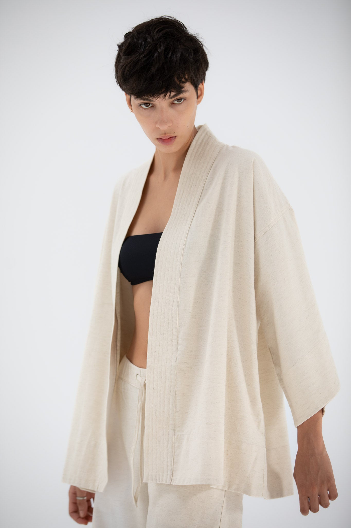 Person wearing a linen kimono jacket on a white background