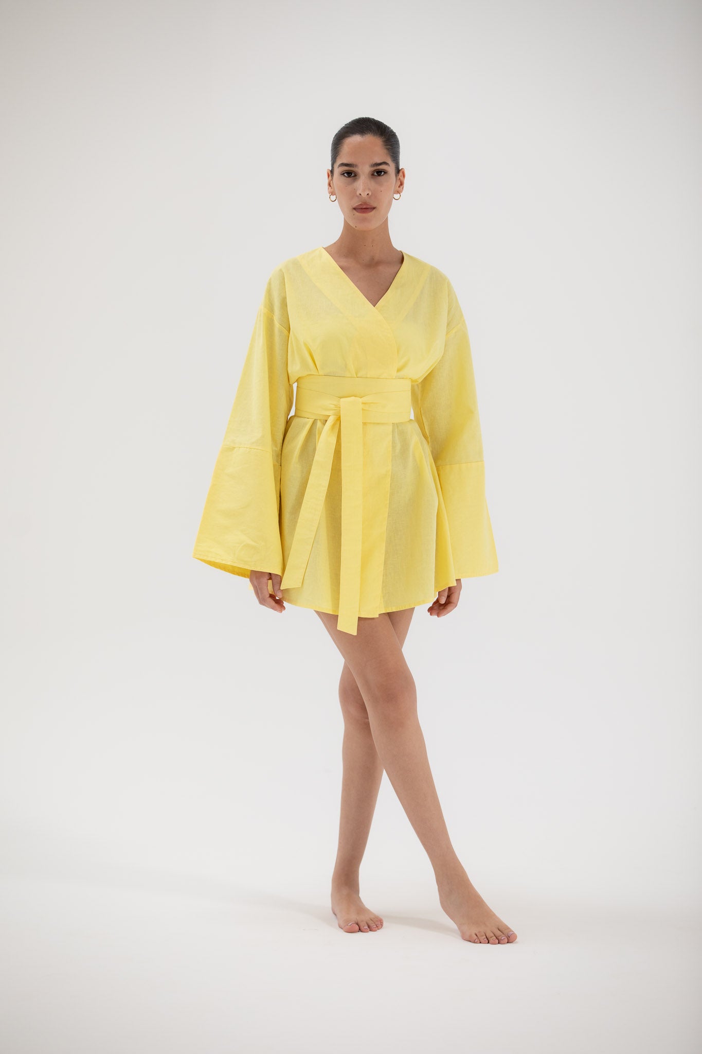 Woman wearing a short kimono inspired dress on a white background