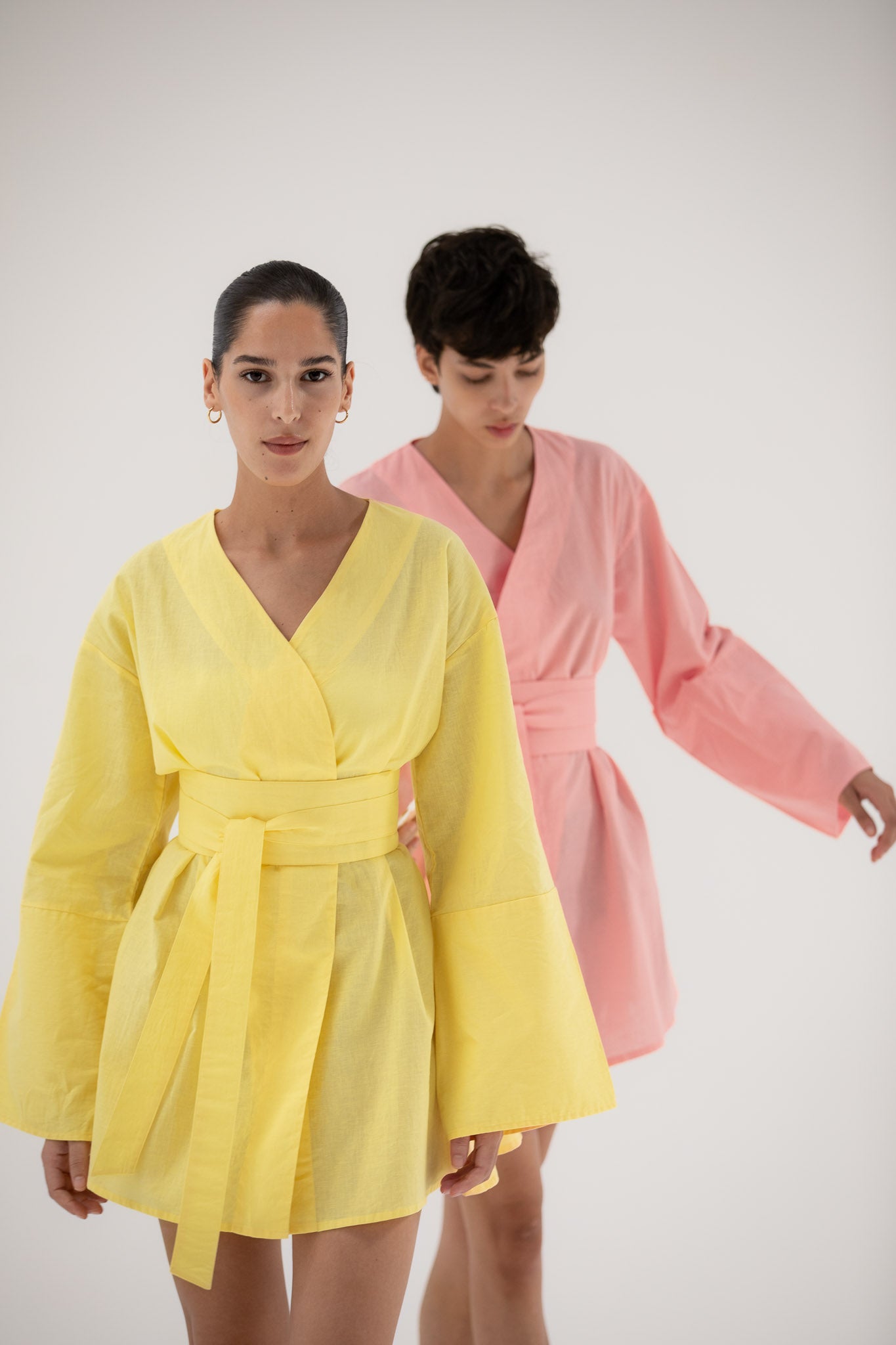 Two women wearing yellow and pink short kimono dresses made of linen designed by atelier mizuni.