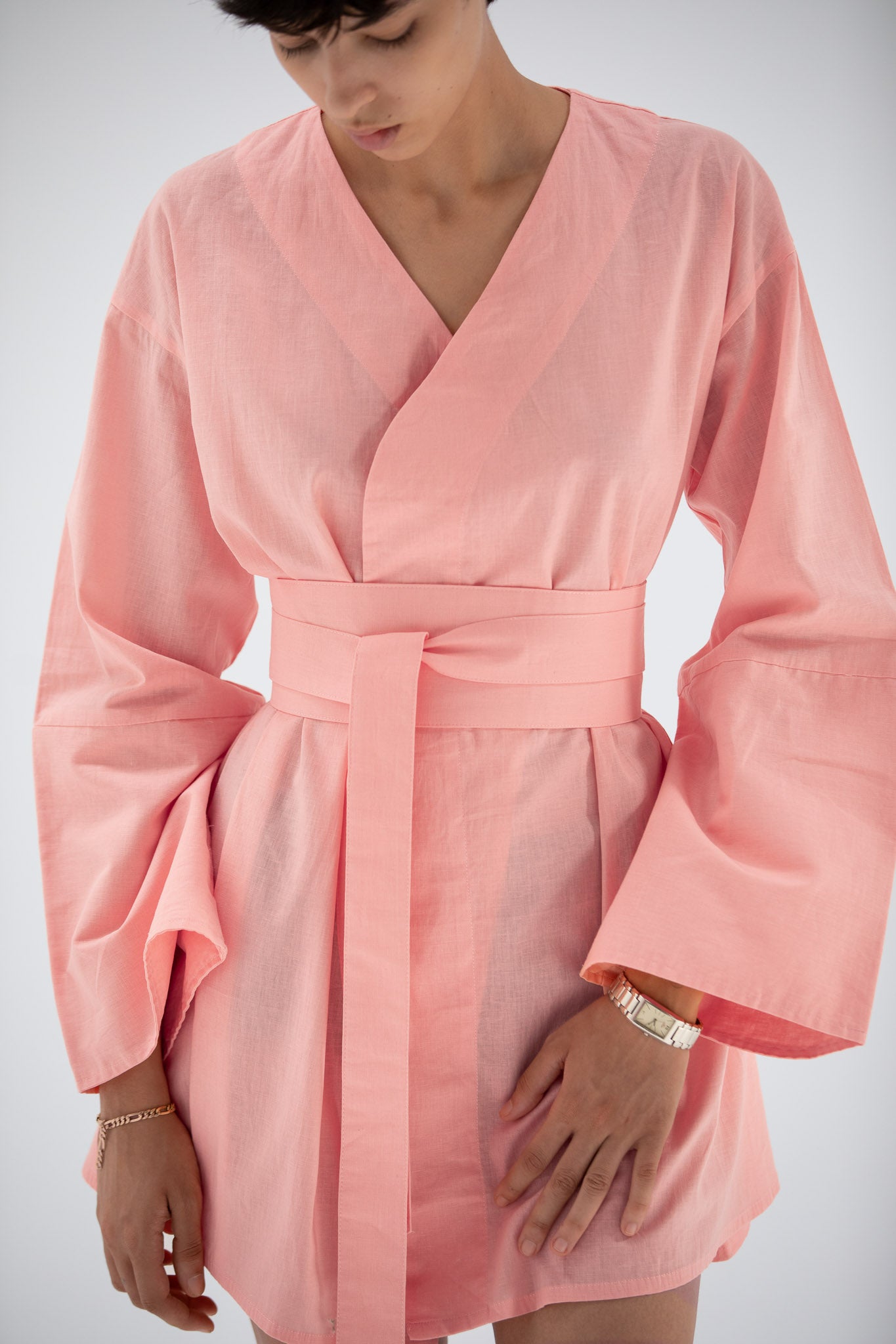 Person wearing a pink short linen kimono dress designed by atelier mizuni.