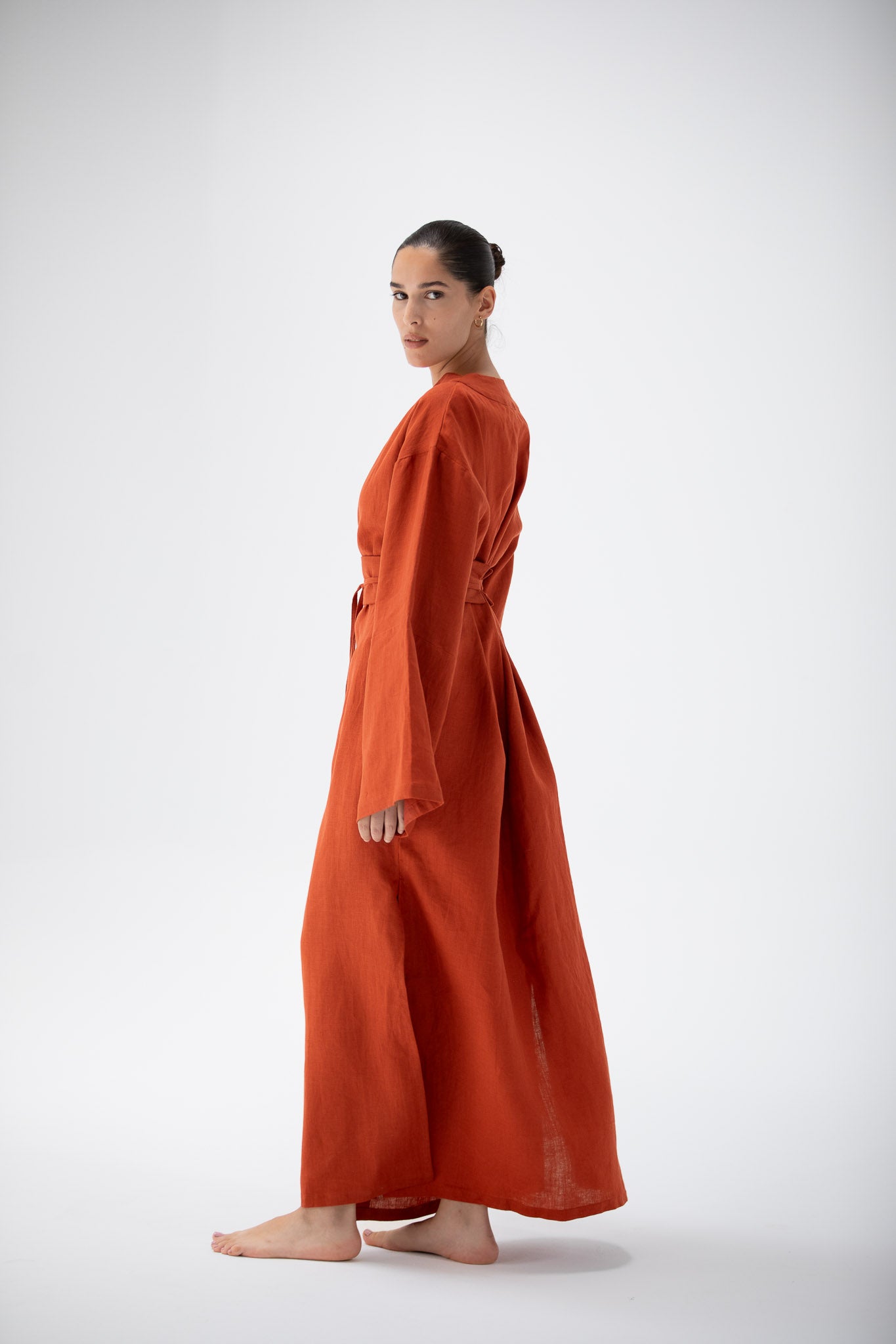 Woman wearing a terracotta linen kimono dress on a white background