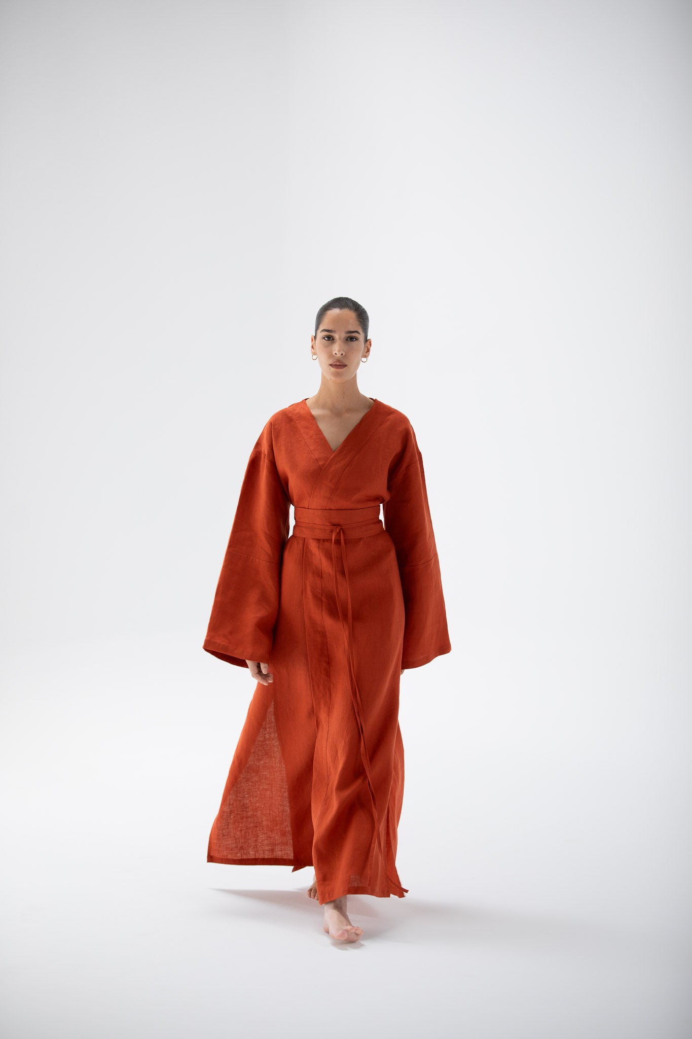 Woman wearing a linen kimono dress outfit in terracotta designed by atelier mizuni.