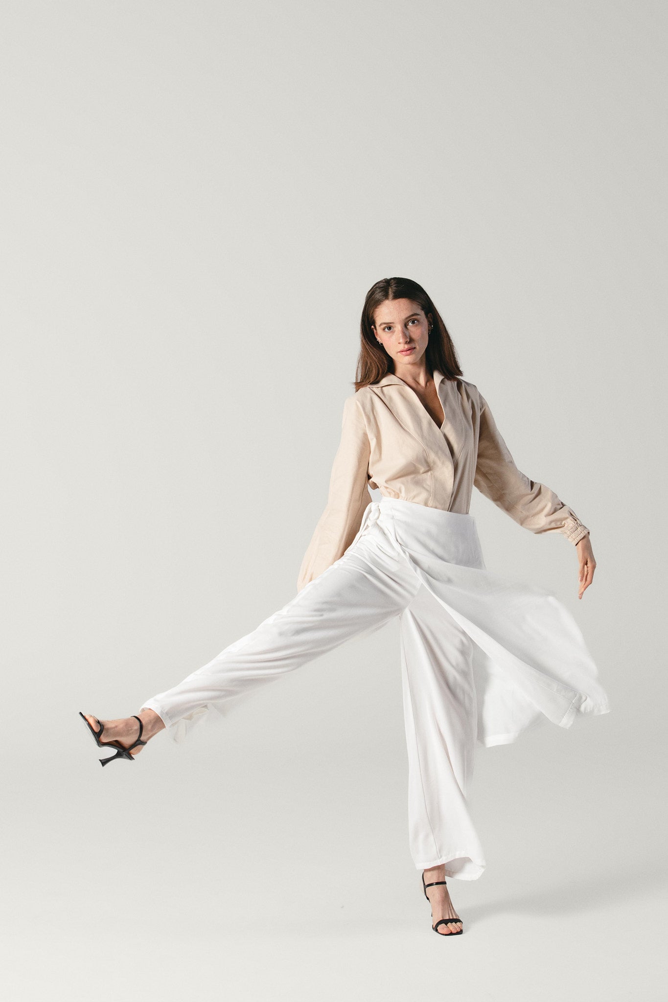 Model wearing a viscose white pants with attachable skirt by Atelier Mizuni. the model is in movement showing the flowy material