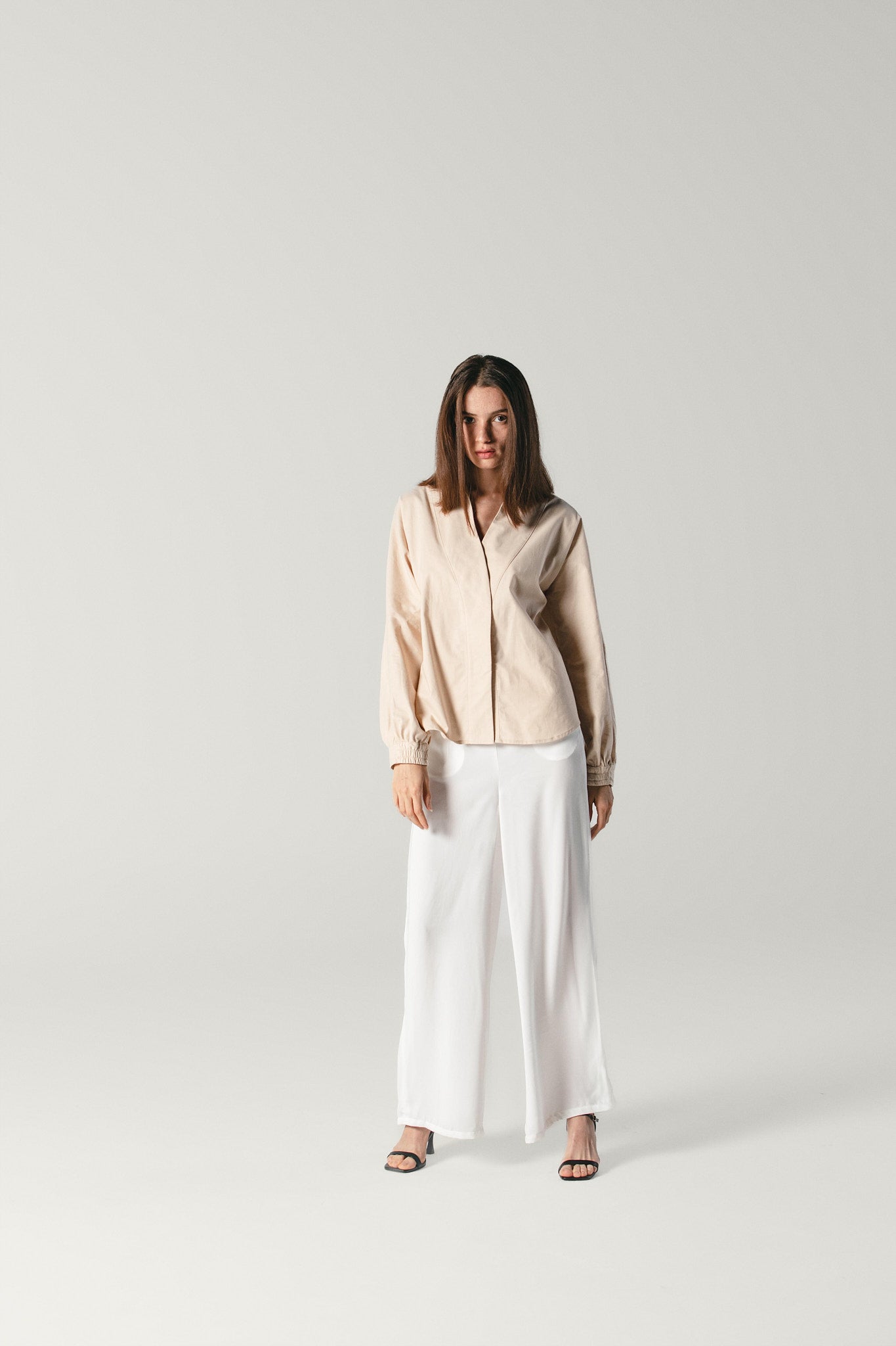 A front wide shot of a model wearing a beige organic poplin shirt made by Atelier Mizuni